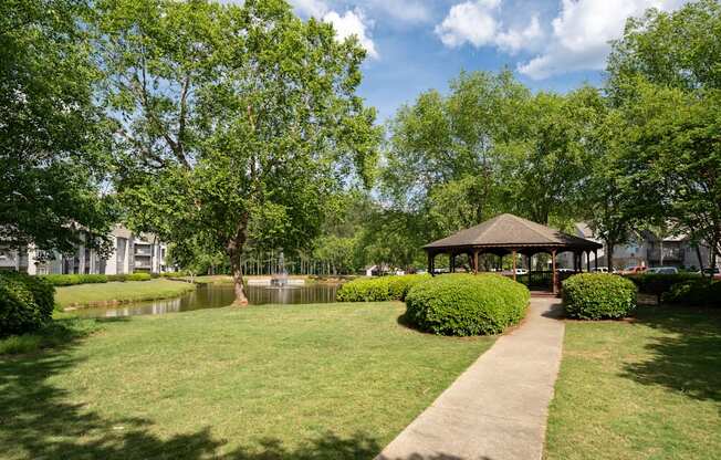 A gazebo is surrounded by greenery in a park.