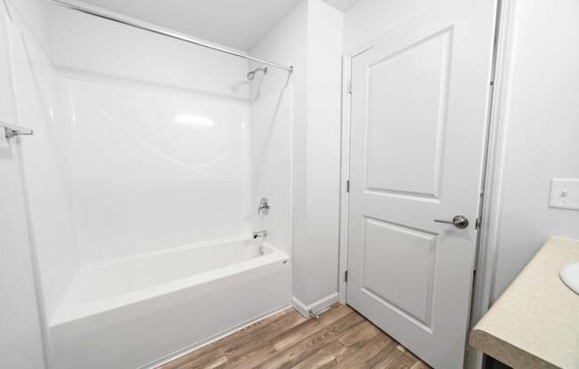 a bathroom with a white bathtub and a white door  at Union at Wiley, Cedar Rapids, Iowa