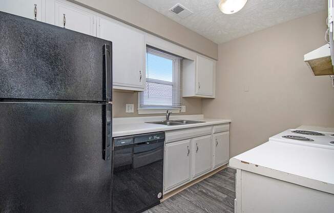 Omaha, NE Maple Ridge Apartments. A kitchen with white cabinets and black appliances