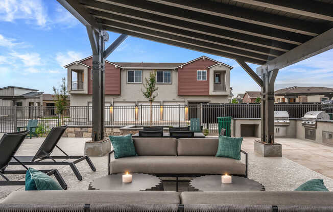 A patio with a couch, chairs, and candles under a roof.
