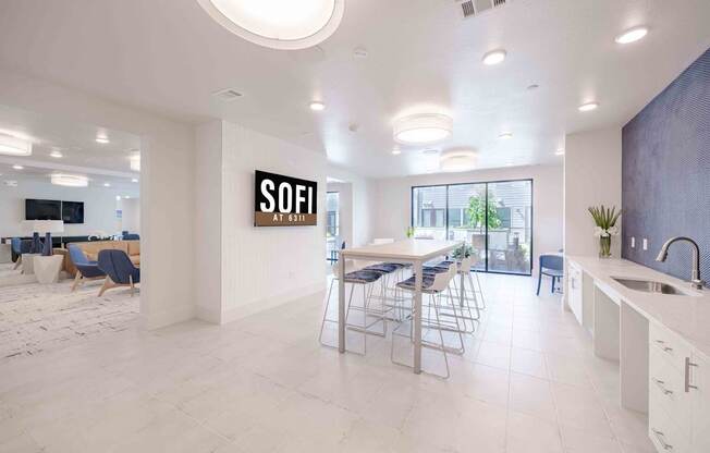 A modern kitchen with a dining area and a sign that says "SOFI" on the wall.
