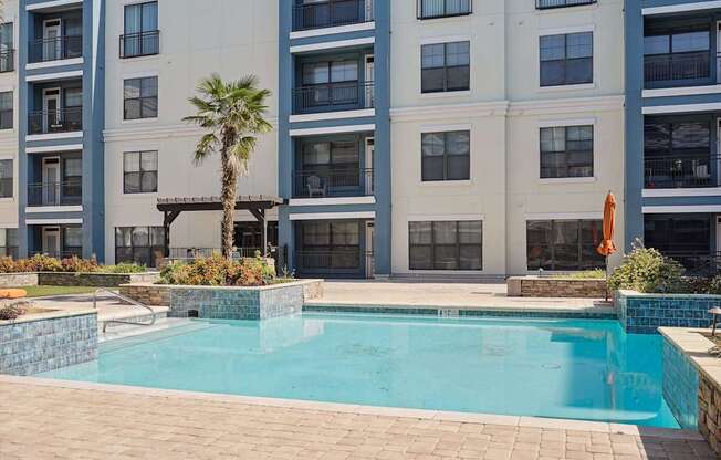 A pool in front of a building with a palm tree.