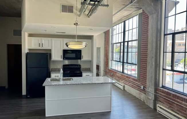 A kitchen with a granite countertop and a black refrigerator.