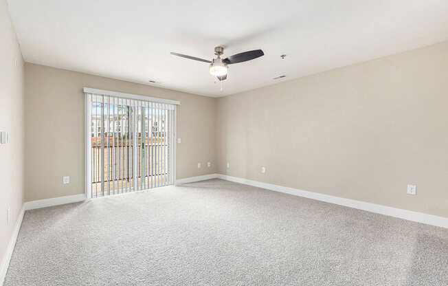 an empty living room with a ceiling fan and a window