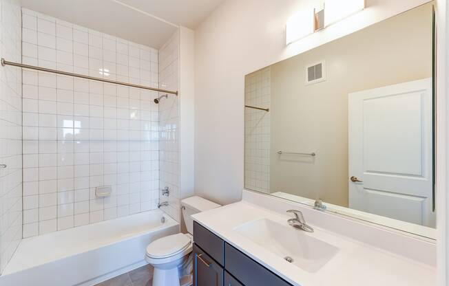 bathroom with large mirror, tub, toilet and vanity at city view apartments in washington dc