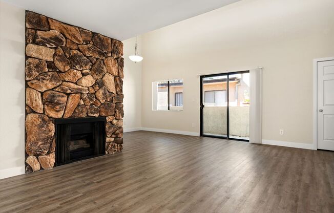 A room with a stone fireplace and wooden flooring.