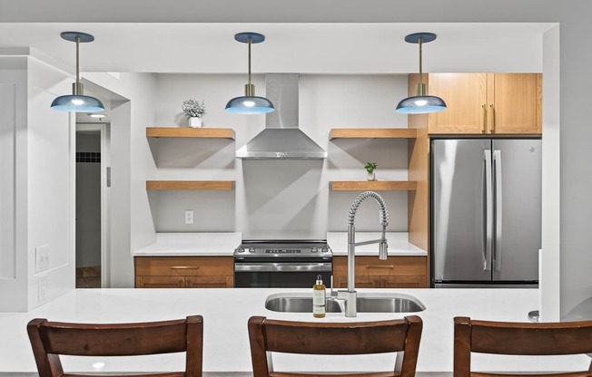 A modern kitchen with a sink, stove, and refrigerator.