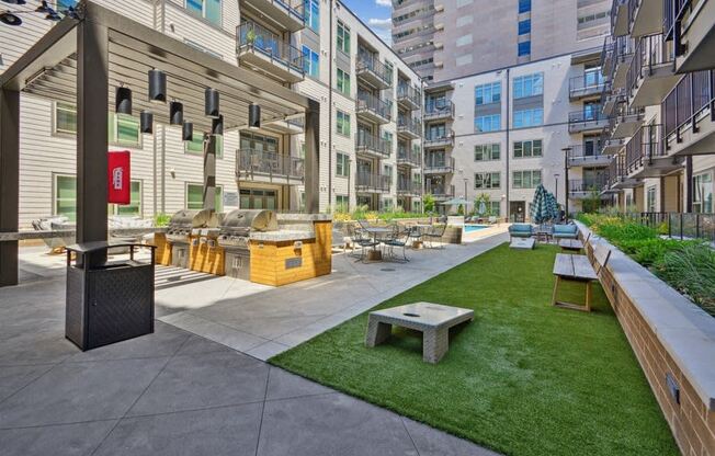 an outdoor lounge area with a picnic table and a grill in an apartment building at Link Apartments® 4th Street, Winston-Salem, North Carolina