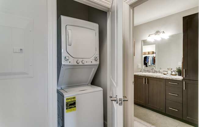 a white washer and dryer sitting on top of a refrigerator in a bathroom