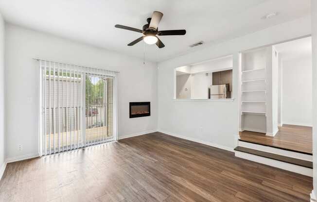 an empty living room with a ceiling fan and a staircase