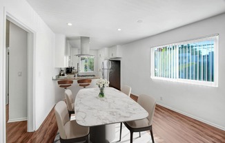 a dining area with a table and chairs and a kitchen in the background