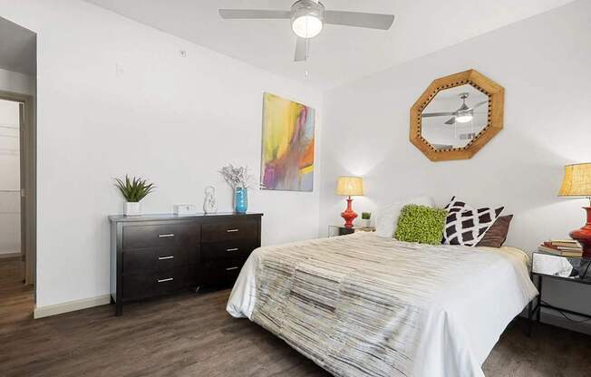 A bedroom with a bed, dresser, and ceiling fan.