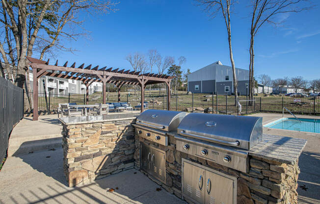 an outdoor entertaining area with a barbecue grill and a pool