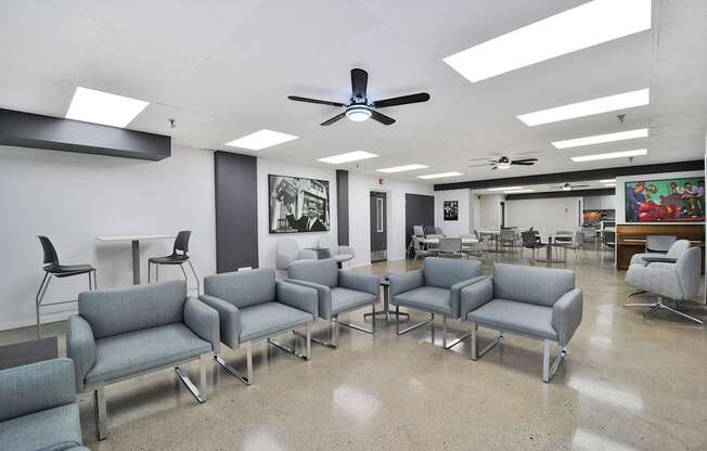 A room with grey couches and a ceiling fan.