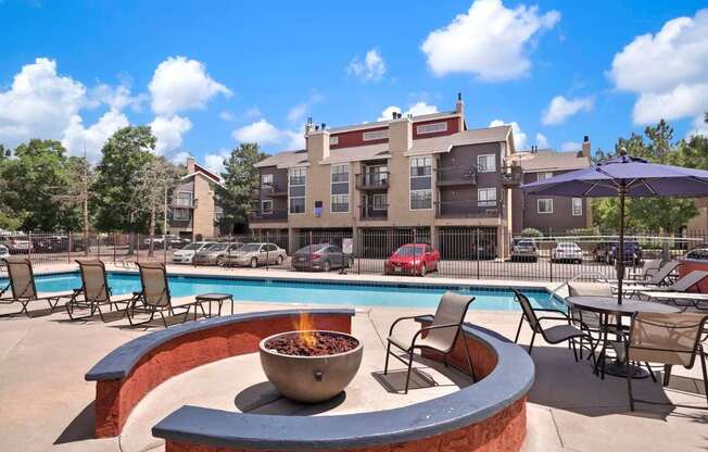A fire pit sits in the middle of a patio with chairs around it.