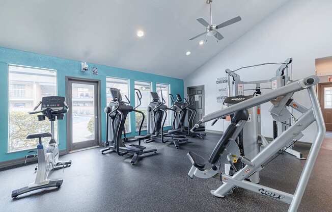 A gym with a variety of exercise equipment including treadmills, stationary bikes, and weight machines.
