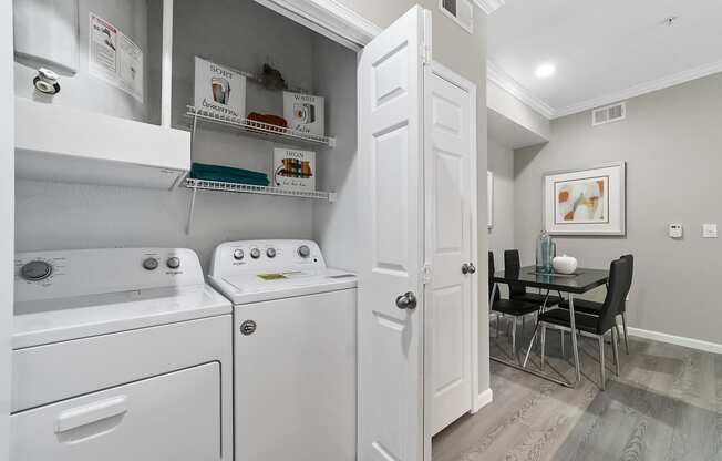 a laundry room with a washer and dryer and a dining room table with chairs