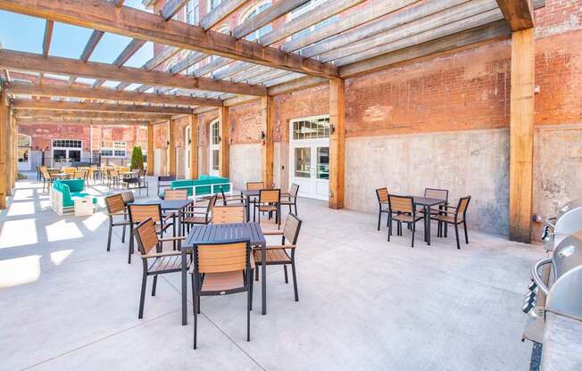A patio with tables and chairs is covered by a roof.