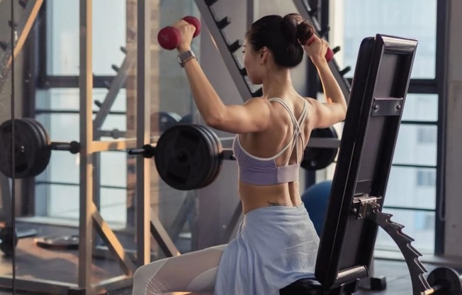 a woman exercising with dumbbells in a gym