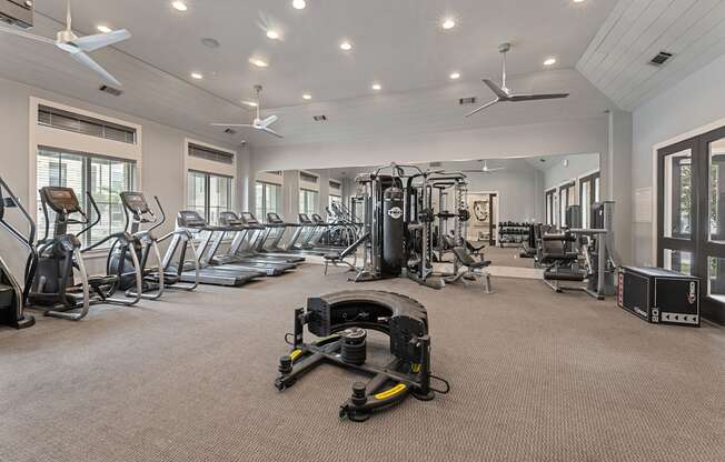 A spacious gym with a variety of equipment including treadmills, elliptical machines, and weight machines.