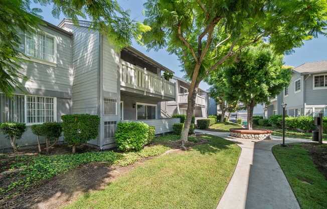 A tree in front of a building with a walkway in between.