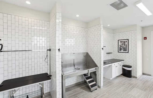 A white tiled bathroom with a sink, mirror, and a bench.