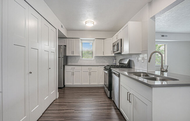 a kitchen with white cabinets and a window at The Crossings Apartments, Michigan, 49508