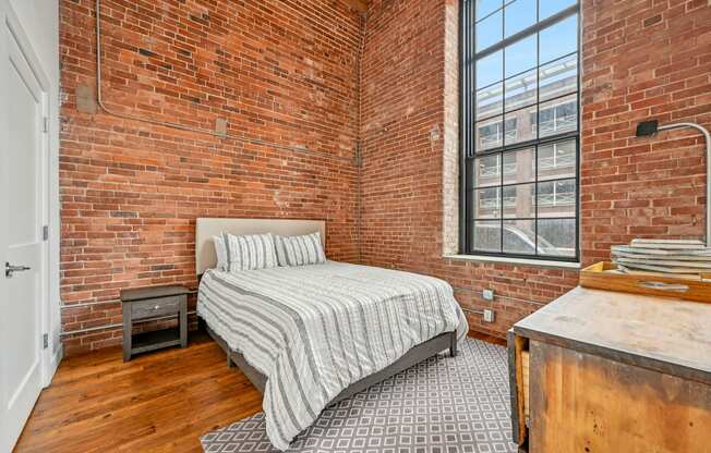 a bedroom with a bed and a brick wall