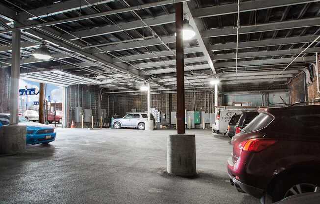 A parking garage with a few cars and concrete pillars.