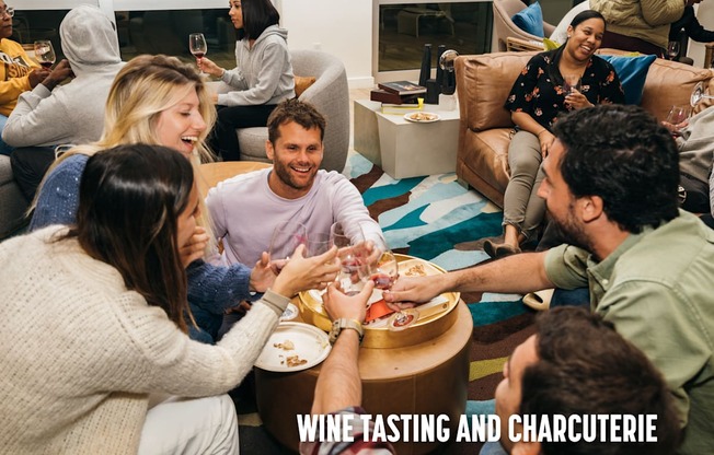 A group of people are gathered around a table enjoying a wine tasting and charcuterie event.