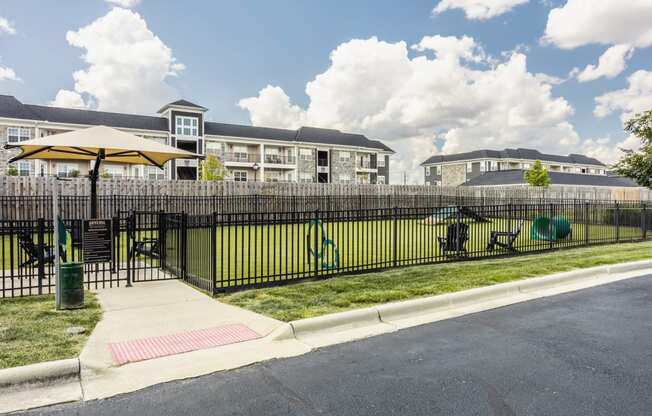 a fenced in yard with a playground and apartments in the background