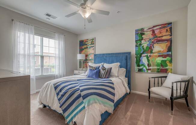 A bedroom with a bed, chair, and painting on the wall.