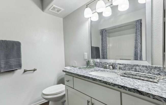A bathroom with a toilet, sink, and mirror.