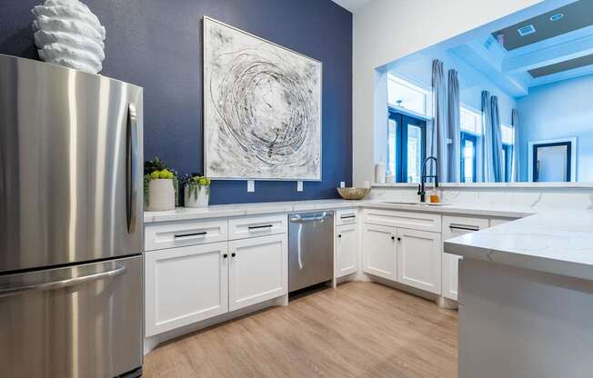 A modern kitchen with a stainless steel refrigerator and white cabinets.
