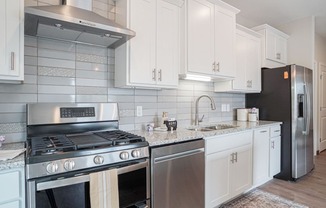 a kitchen with white cabinets and stainless steel appliances at The Yards and Backyards, Minnesota, 55075