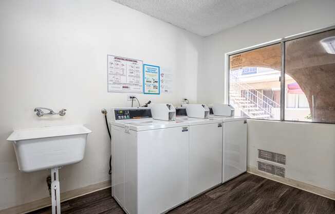 a laundry room with washing machines and a sink and a window