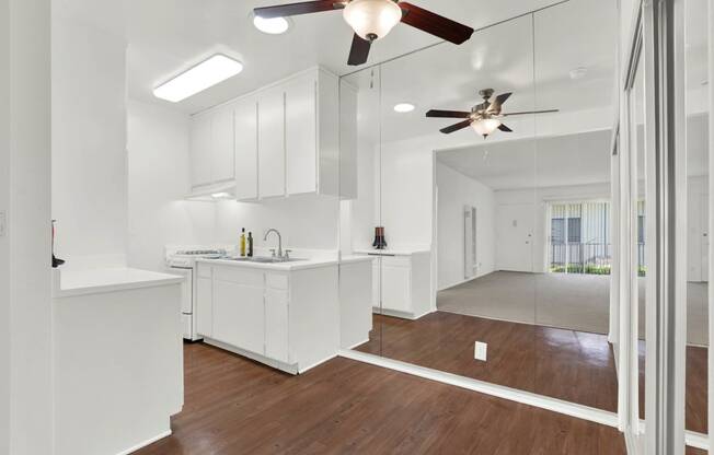 a kitchen with white cabinets and a ceiling fan at Olive Tree Apartments, California, 90503