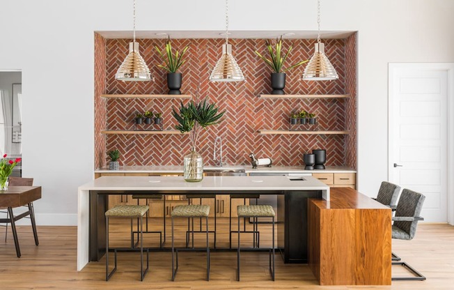 a kitchen with a large island with stools and pendant lights