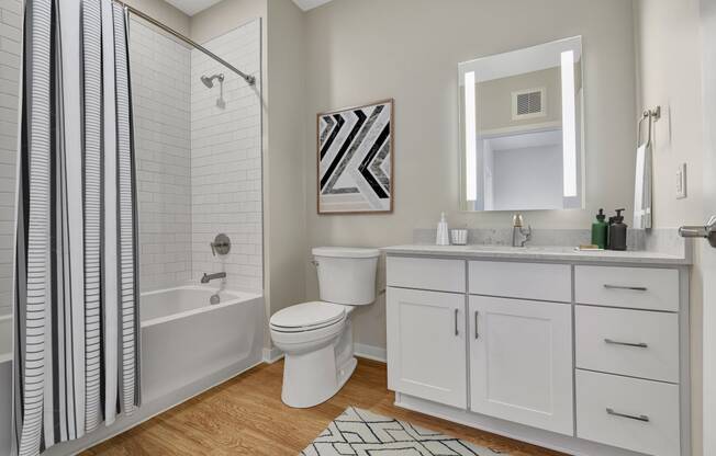 a bathroom with white cabinets and a white and black shower curtain