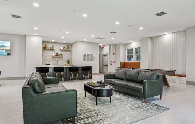 A living room with a green couch, a black coffee table, and a television.