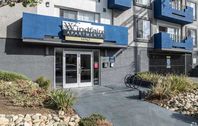 The image shows the front of the Windfaith Apartments building with a blue awning and glass doors.
