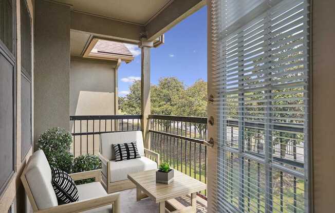 A patio with a white chair and a small table with a plant on it.