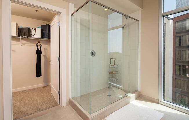 a glass shower in a bathroom next to a window