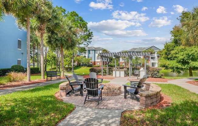 A fire pit with a circular seating area surrounded by lush greenery at Wynnfield Lakes Apartments in Jacksonville, FL