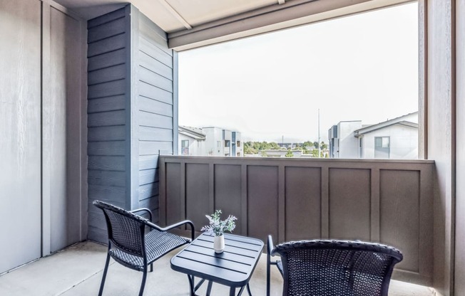 a balcony with a table and chairs and a large window