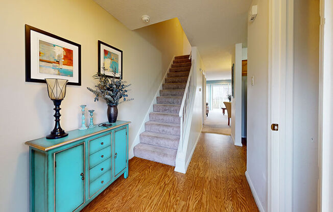 a living room with stairs and a blue dresser