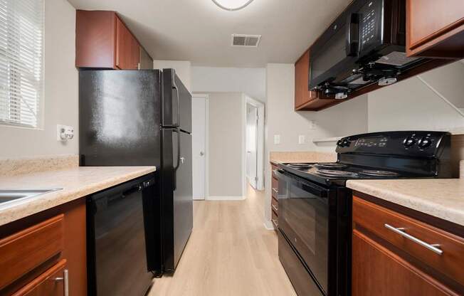 A kitchen with black appliances and wooden cabinets.