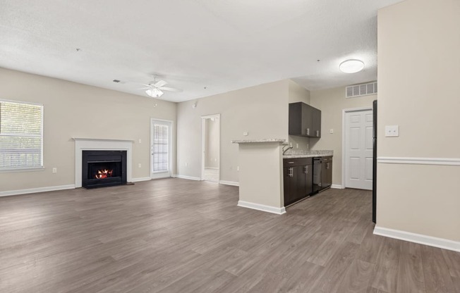 an empty living room with a fireplace and a kitchen