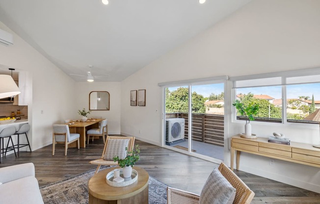 a living room with a dining room table and chairs and sliding glass doors