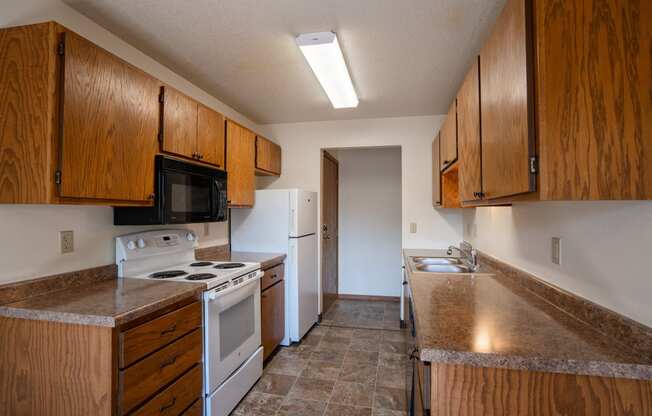 an empty kitchen with white appliances and wooden cabinets. Fargo, ND Southview Village Apartments